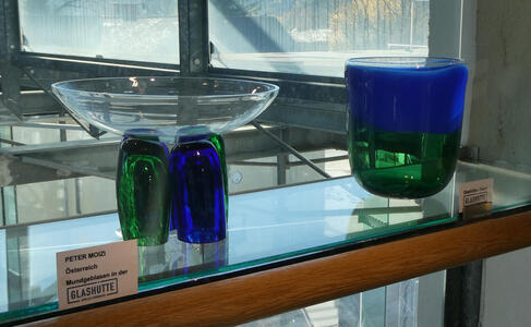 At left, a clear bowl on two “supports”, one green and one blue. At right, a large glass blow with a blue top and green bottom