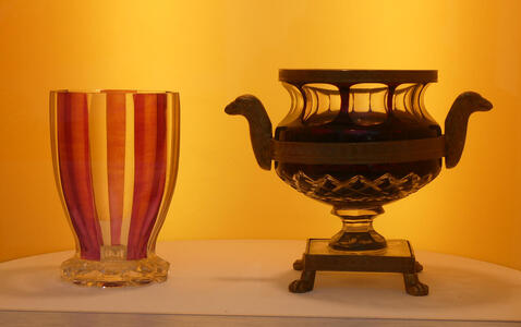 At left, drinking glass with red vertical stripes; at right, what looks like a funerary urn with handles.