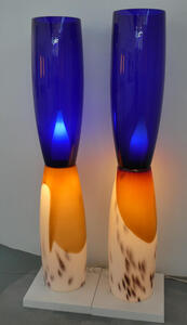 Two floor lamps. The bases are white with orange spots, then transitioning to orange. The upper part is cobalt blue. They look like large drinking glasses.