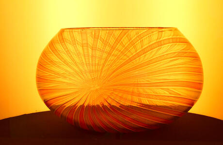 Orange glass bowl with lines radiating out from a central point.