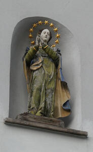 Woman in green robe, hands folded in prayer. Above her head, a  halo of stars.