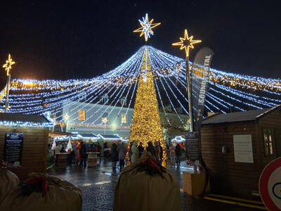 Gold Christmas tree, with strands of blue lights extending from top to nearby buildings