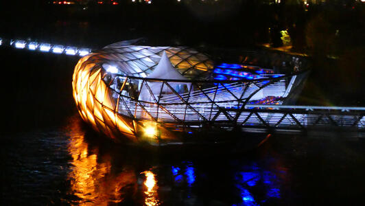 Murinsel at night, lit up in gold and blue lights.