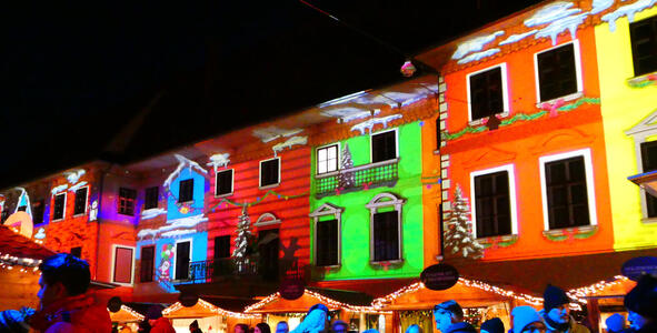Images of red, blue, green, and yellow houses projected onto buildings in Karmeliterplatz