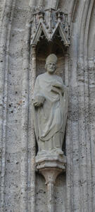 Statue of bearded bishop with mitre and in robes; statue is in a niche.