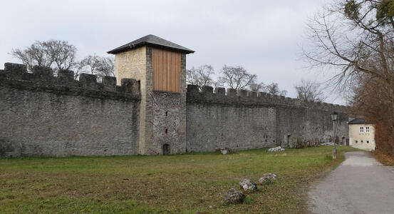 Stone wall with “teeth” at top; in the middle of the wall, a guard tower.