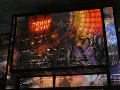 One of the projected panels with words Trump Kyiv on a building in neon lights