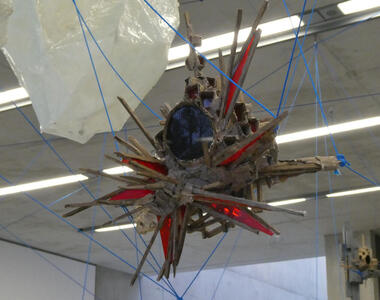 Abstract sculpture with sharp angles and red transparent plastic; it is hanging from ceiling