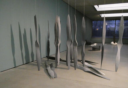 Array of vaguely propeller-shaped pieces of metal suspended from ceiling