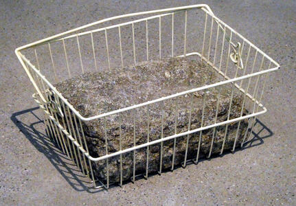 Wire-frame shopping basket with large rectangular stone in it