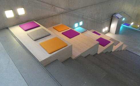 Stairway with cushions in magenta, gold, and gray placed on the area next to the stairs.