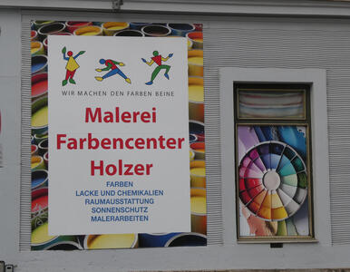 Store that sells paint, logo has people dancing; people are made up of colored geometric forms. At right, a color wheel.