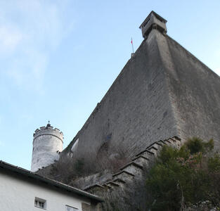View of fortress taken at steep angle from below. A round tower is at the left.