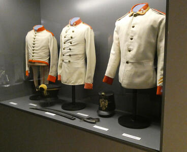 Display case with three Prussian-style military dress coats