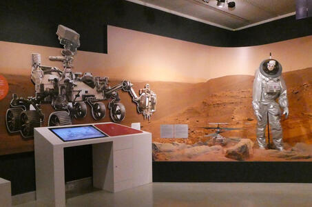 Display about Mars; large cutout of Mars rover at left; mannequin in spacesuit at right