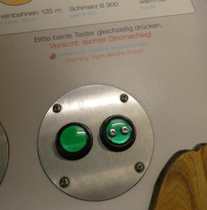 Two green buttons, one with two metal contacts on it