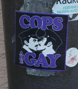 Sticker showing two police with moustaches kissing. Text: Cops are gay