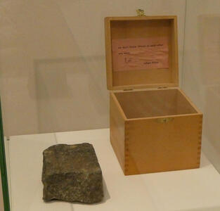 Open wooden box with square stone that would fit in the box next to it. In the lid of the box: “we don’t throw stones at each other any more - robert filliou”