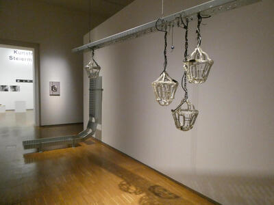 Metal baskets hanging from a horizontally placed metal bar that is itself hanging from the ceiling
