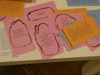 Paper cards with questions such as: If you were in a karaoke bar, which song would you sing? If you could invent a holiday, what would it be called & what would you celebrate?