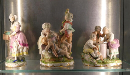 Ceramics of a woman with a basket, children playing, and people standing around a table