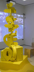 All-yellow post with arrow signs pointing in all direcctions. At bottom, a life preserver and a suitcase