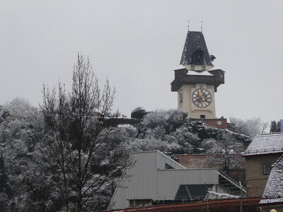 The Graz Clock Tower with a light dusting of snow. At left, trees with snow on them