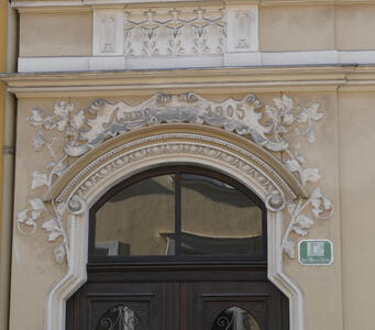 Door with intricate carving above an arched frame; text on frame is Anno 1905