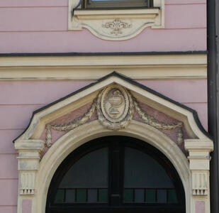 Reliefwork above arched doorway; featured is a cup with a snake curled around it.