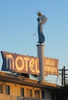 Angel in blue garment, with halo, facing away from sign