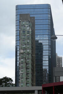 Old, decrepit building in front of modern taller building.
