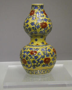 yellow vase with blue vines and red flowers