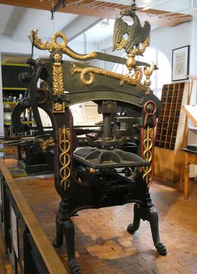 Printing press decorated with gold ornamentation and an eagle on top.