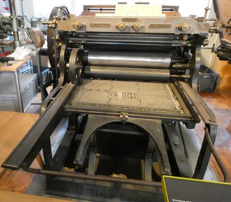 Modern printing press with a metal sheet for the type and rollers for the paper