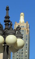 Old style lamp post in foreground; skyscraper with gold trim on top in background