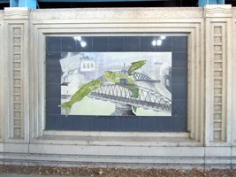 Tile mural on underpass showing green ish leaping over bridges