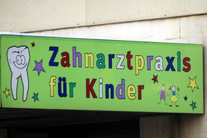 Sign with multicolored letters, a cartoon tooth, and stick figure people