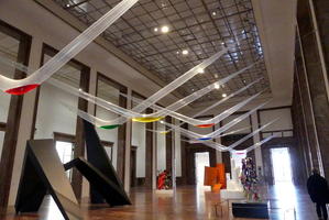 Glass “u” shapes hanging from ceiling, with colored “liquid” at bottom