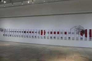 Wire “clouds” hanging from ceiling; abstract red painting in background.