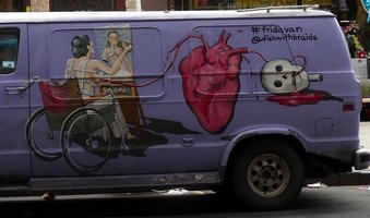 Woman in wheelchair painting self-portrait; large anatomically correct heart, and skull