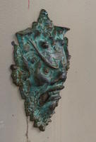 small bronze gargoyle on side of building