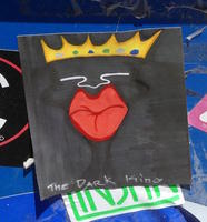 Black face, red lips, gold crown; titled “The Dark King”
