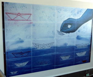 Hand placing paper boats in water; each boat has writing in a different language.