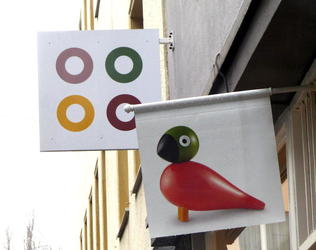 Flag with stylized bird in front, four ring logo in back.
