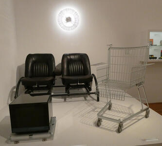 Two standard chairs and one made from a shopping cart.