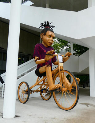 large sculpture of woan on three wheeled bicycle