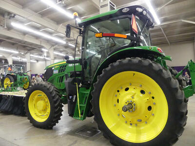 Green tractor with large rear wheels and small front wheels. Wheels are yellow