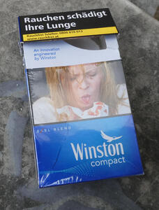 Cigarette Package. Text: Rauchen schädigt Ihre Lunge. Photo shows a woman spitting up bood into a handkerchief.
