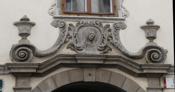 Reliefwork of woman with halo. Fancy scrollwork at left and right