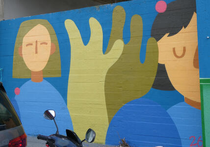 Two people waving hands at viewer.
